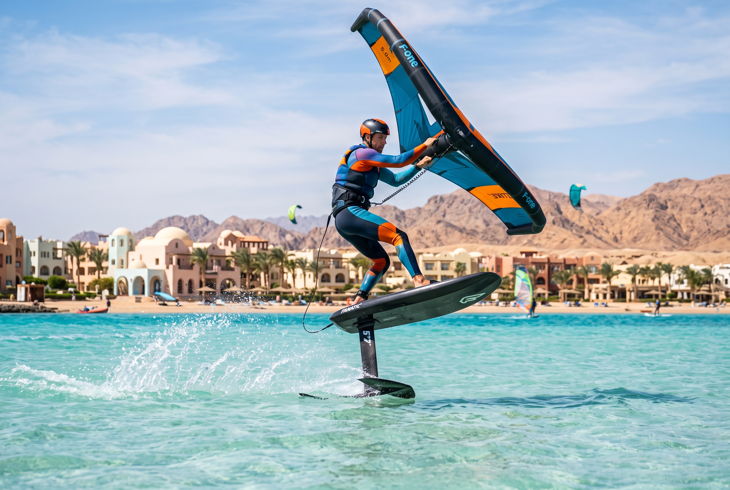 Wing foiler on a hydrofoil holding a wing across a flat turquoise lagoon at El Gouna, Egypt, with desert and resort behind